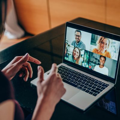 Shot of young woman talking to her friends in video call from home. Multi-ethnic group of people using laptop for a online meeting in video call. Friends having online conversation during quarantine.